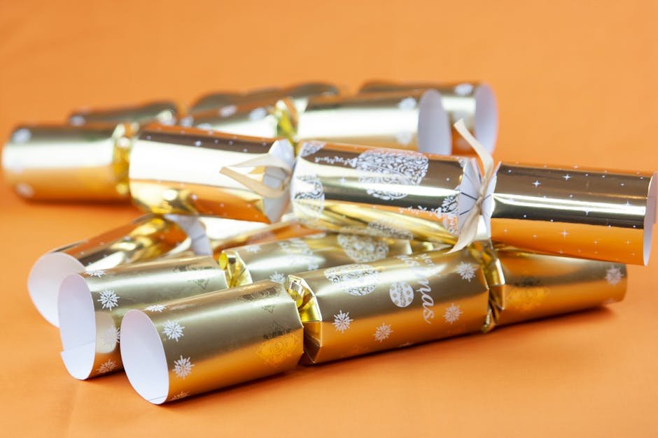 Close-up of gold foil Christmas crackers displaying festive patterns against an orange backdrop.